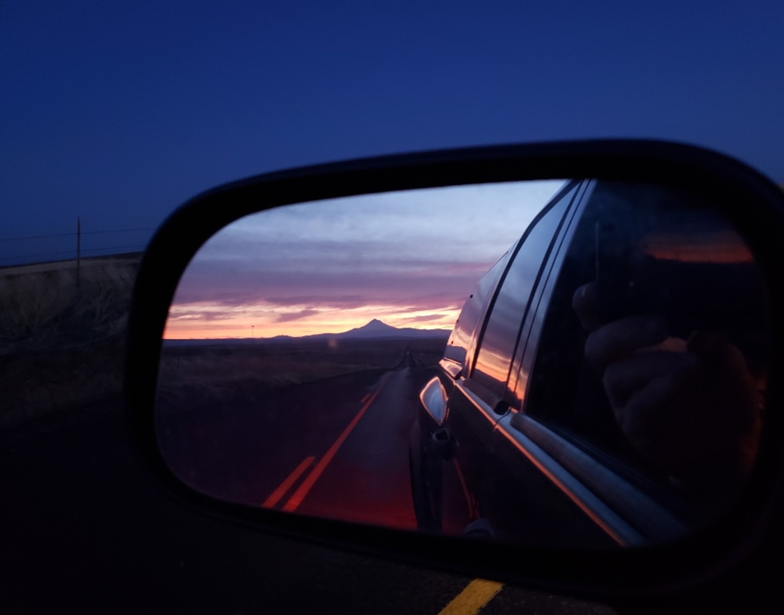 Mountain sunset reflected in a vehicle side mirror